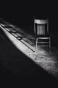 a black and white photo of a chair with the shadow cast on it's back