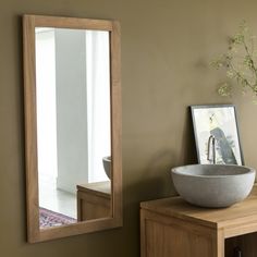 a bowl is sitting on top of a wooden table next to a mirror and vase