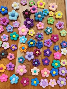 there are many different colored flowers on the wooden table and one is made out of plastic