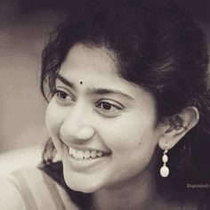 a black and white photo of a woman with earrings on her head smiling at the camera