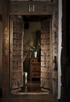 an open wooden door leading into a room with flowers in vases on the table