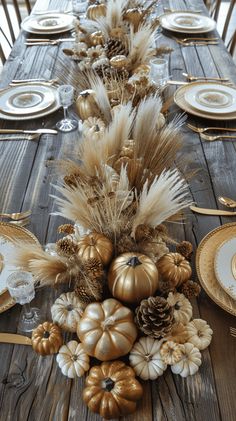 the table is set with gold and white plates, silverware, and golden pumpkins