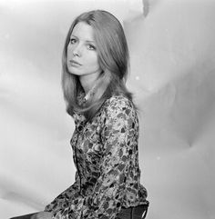 black and white photograph of a woman sitting on top of a chair with her legs crossed