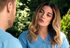 a woman in scrubs talking to a man