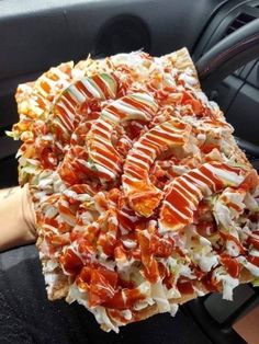 a person holding up a large pizza covered in toppings