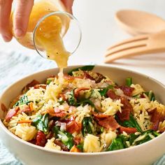 someone is pouring orange juice into a bowl of pasta with bacon and spinach on the side