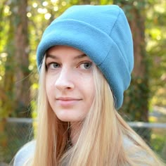 a woman with long blonde hair wearing a blue beanie and looking at the camera