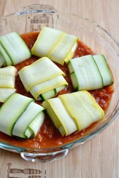 a glass bowl filled with sliced cucumbers on top of a wooden table