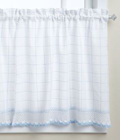 a white curtain with blue trim hanging on a window sill