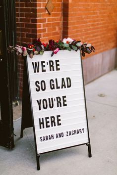 a sign on the sidewalk that says we're so glad you're here