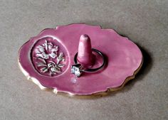 a pink ring holder with a flower design on it