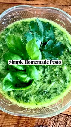 a glass bowl filled with pesto on top of a wooden table