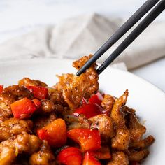 a white plate topped with fried chicken and veggies next to chopsticks