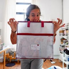 a woman holding up a large bag in front of her face and making a funny face