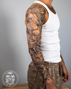 a man with a lion tattoo on his arm and shoulder, standing in front of a table