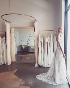 a bride's dress hangs in front of a mirror and mannequins