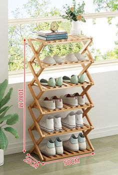 a wooden shoe rack with shoes on top and bottom shelves next to a potted plant