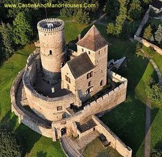 an aerial view of a castle in the middle of trees and grass, looking down on it