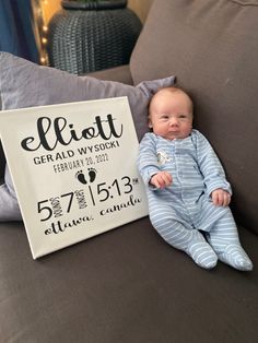 a baby laying on top of a couch next to a sign