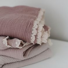 three folded blankets stacked on top of each other with lace trim around the edges and bottom