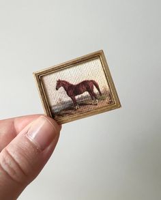 a hand holding up a miniature picture of a horse