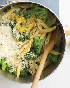 a pan filled with pasta and broccoli covered in parmesan cheese next to a wooden spoon