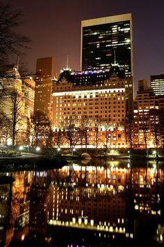 the city is lit up at night with lights reflecting in the water and buildings on both sides