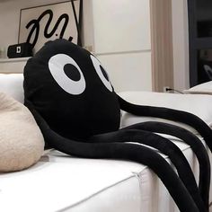 an octopus pillow sitting on top of a white couch next to a stuffed animal toy