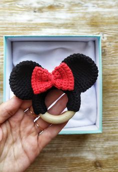 someone is holding up a crocheted mickey mouse ear with a red bow on it