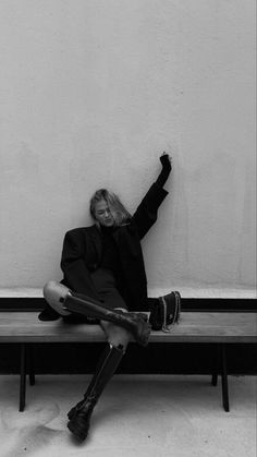 a woman sitting on a bench with her arms in the air and one hand up