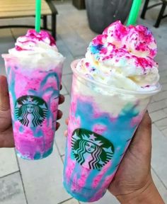 two starbucks drinks with sprinkles on them are being held by someone's hand