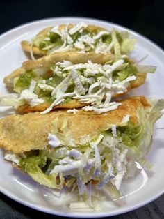 two crepes filled with lettuce and cheese on top of a white plate