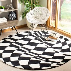 a black and white rug with a chair in front of it on the floor next to a potted plant