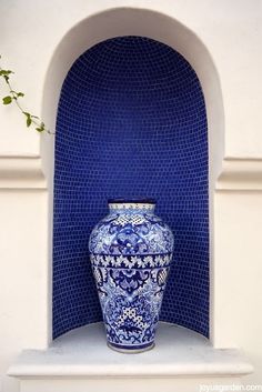 a blue and white vase sitting on top of a shelf in front of a wall