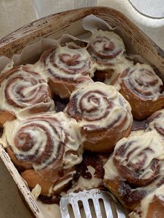 a box filled with cinnamon rolls and a fork