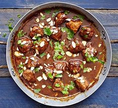 a pan filled with meatballs and sauce on top of a wooden table