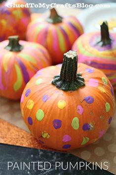 painted pumpkins sitting on top of a table with polka dot paint all over them