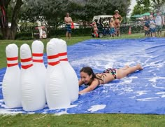 a woman laying on top of a giant inflatable bowling ball pool with four white bowling pins