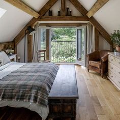 a bedroom with a bed, dresser and window in the atticed room that has wooden beams