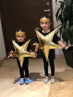 two young children holding gold star shaped balloons