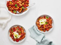 three bowls filled with food sitting on top of a white table next to napkins