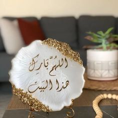 a white and gold plate sitting on top of a wooden table next to a plant