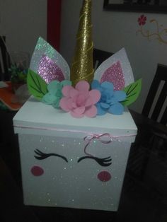 a box with a unicorn's face on it and flowers in the middle, sitting on a table