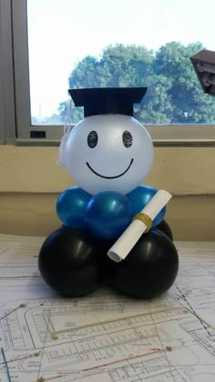 a balloon in the shape of a graduate sitting on top of a table with a diploma