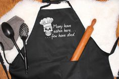 a black apron with a skull on it and cooking utensils