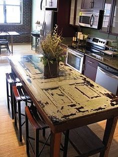 a kitchen with an island made out of old doors and wood planks in the center