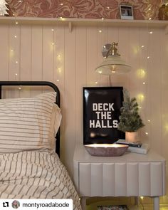 there is a bed with lights on the wall above it and a sign that says deck the hall's