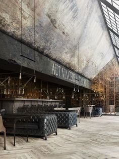 the inside of an empty restaurant with wooden floors and black leather chairs, tables and chandeliers