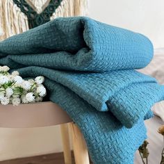 a blue blanket sitting on top of a wooden table next to flowers and a vase