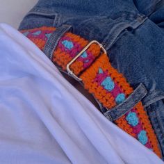 an orange and blue crocheted belt is on someone's jeans